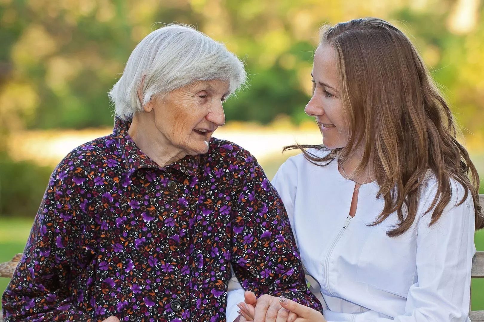 Eine Frau hält die Hand einer älteren Frau und zeigt damit Zuneigung und Unterstützung